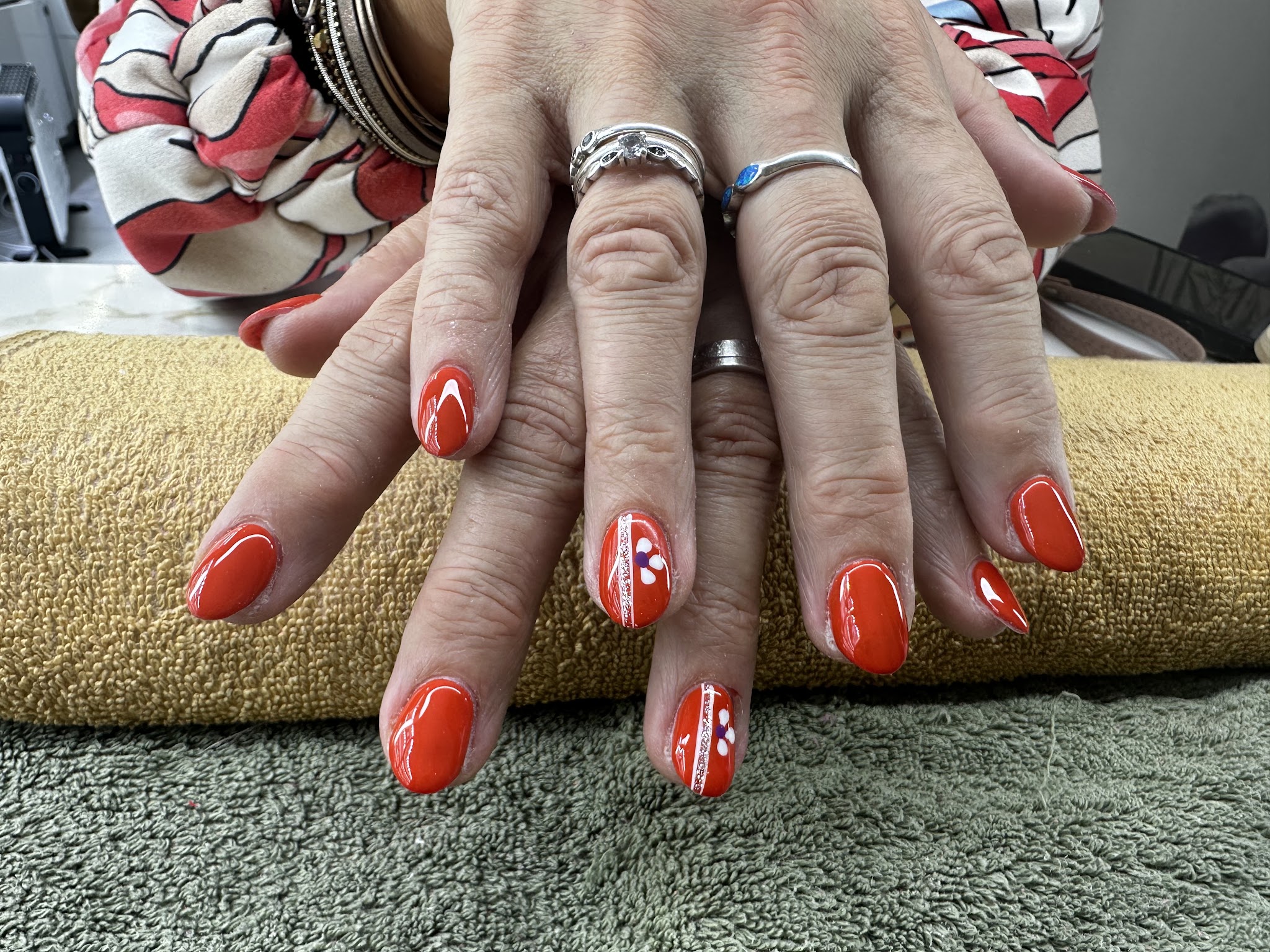 Oranje nagels met witte details op een beige handdoek