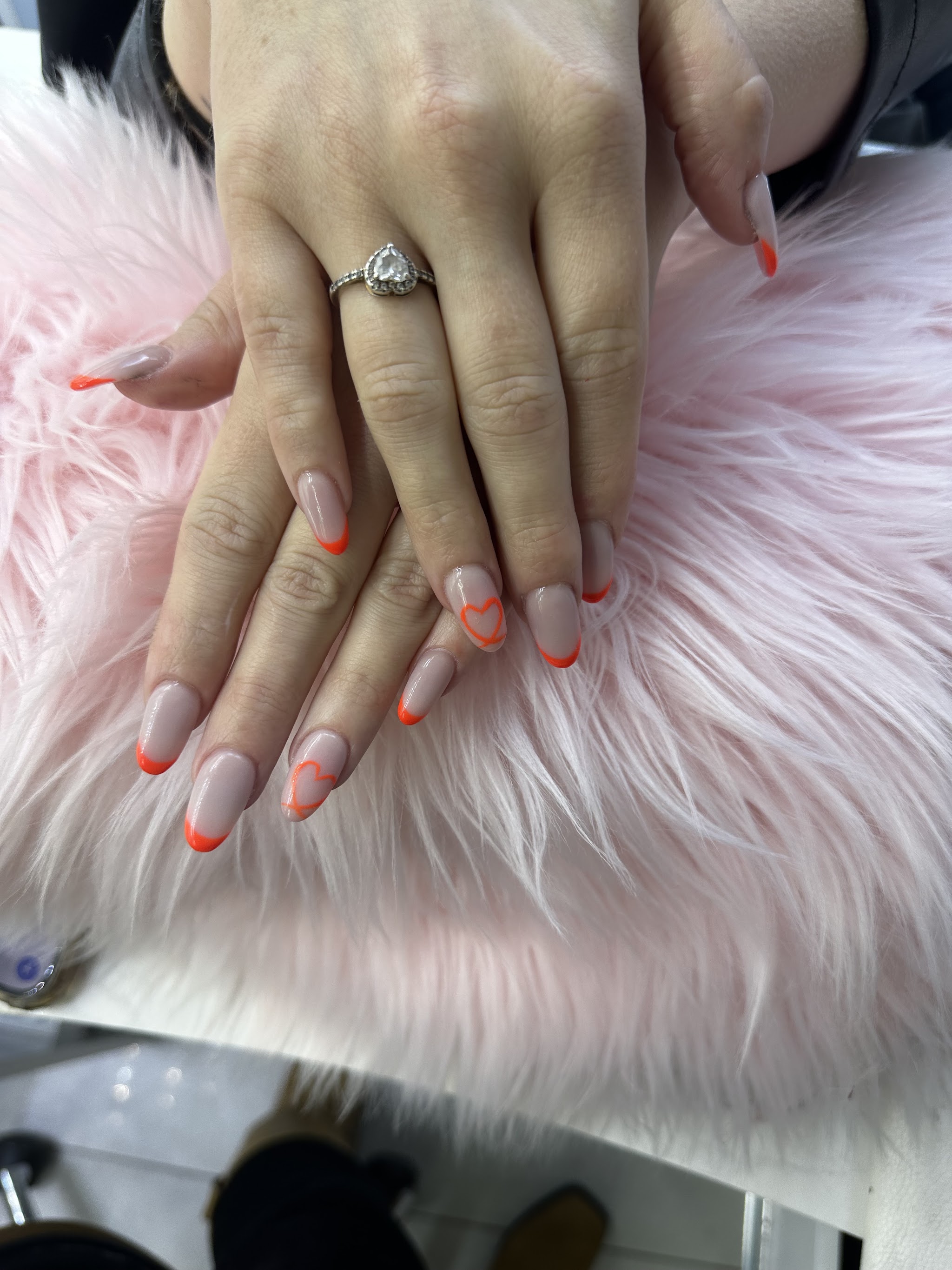 Nude nagels met oranje French op een roze pluche kussen